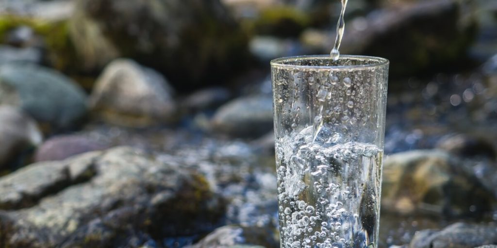 A Glass Of Water With Rocks In The Background